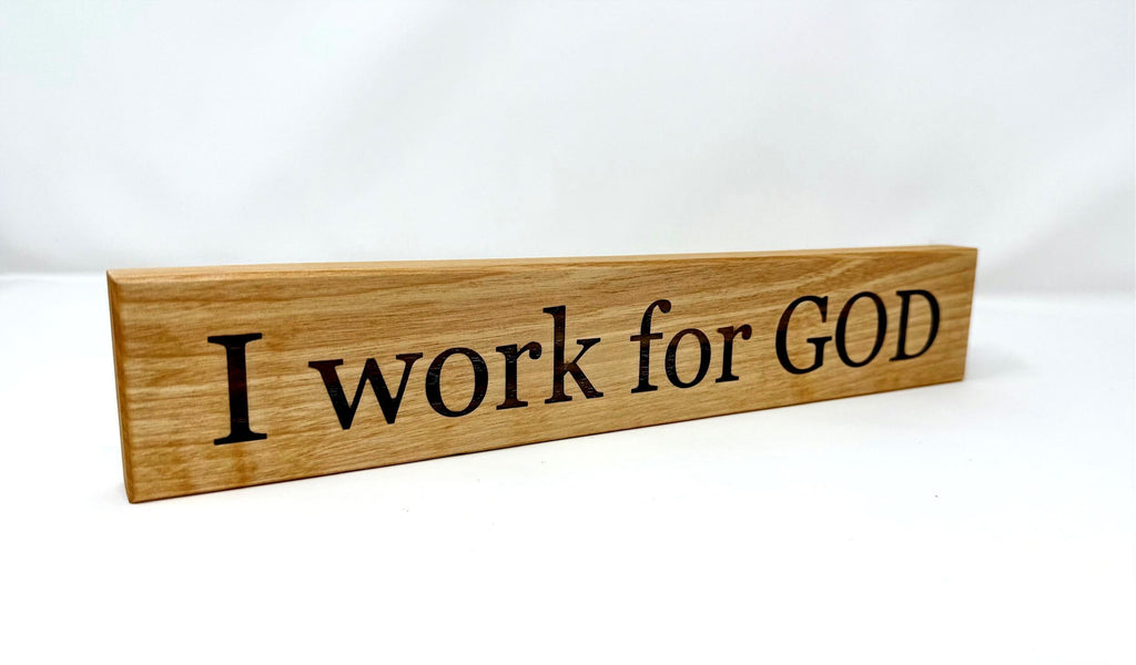 Wooden sign with 'I work for GOD' text on a white background